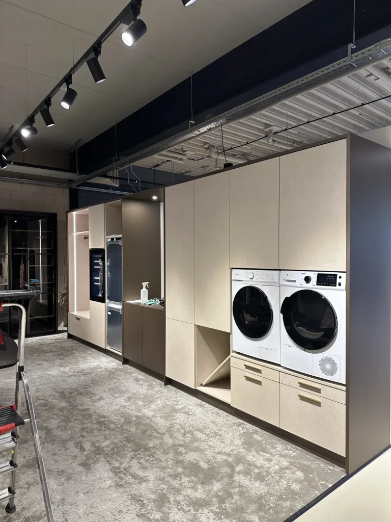 Beige wasmachinekast op maat met apparatuur, werkblad en gesloten bergruimte